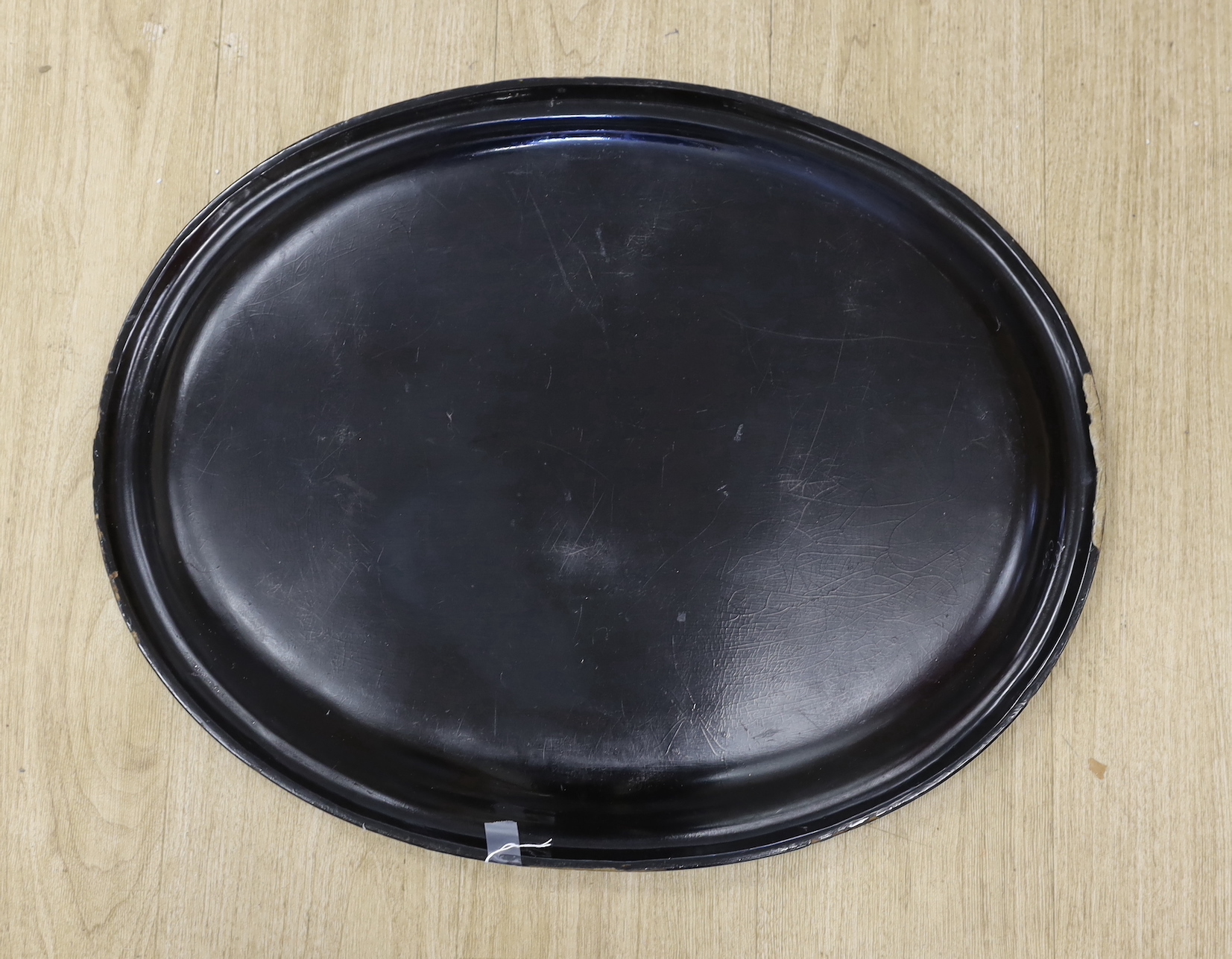 A Regency oval gilt and japanned papier mache tray, designed with a thistle border, 63cm wide